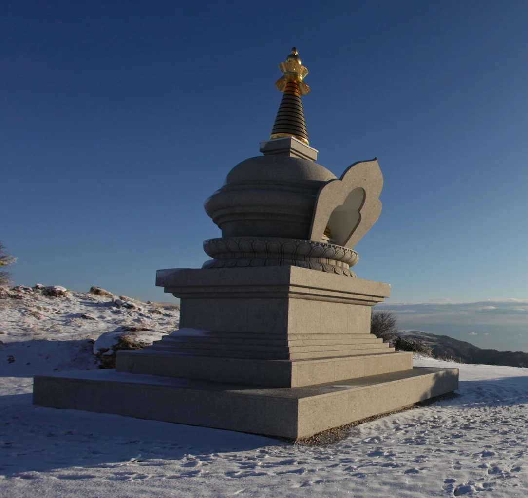 Granite Buddhist stupa on a snowy mountain ridge